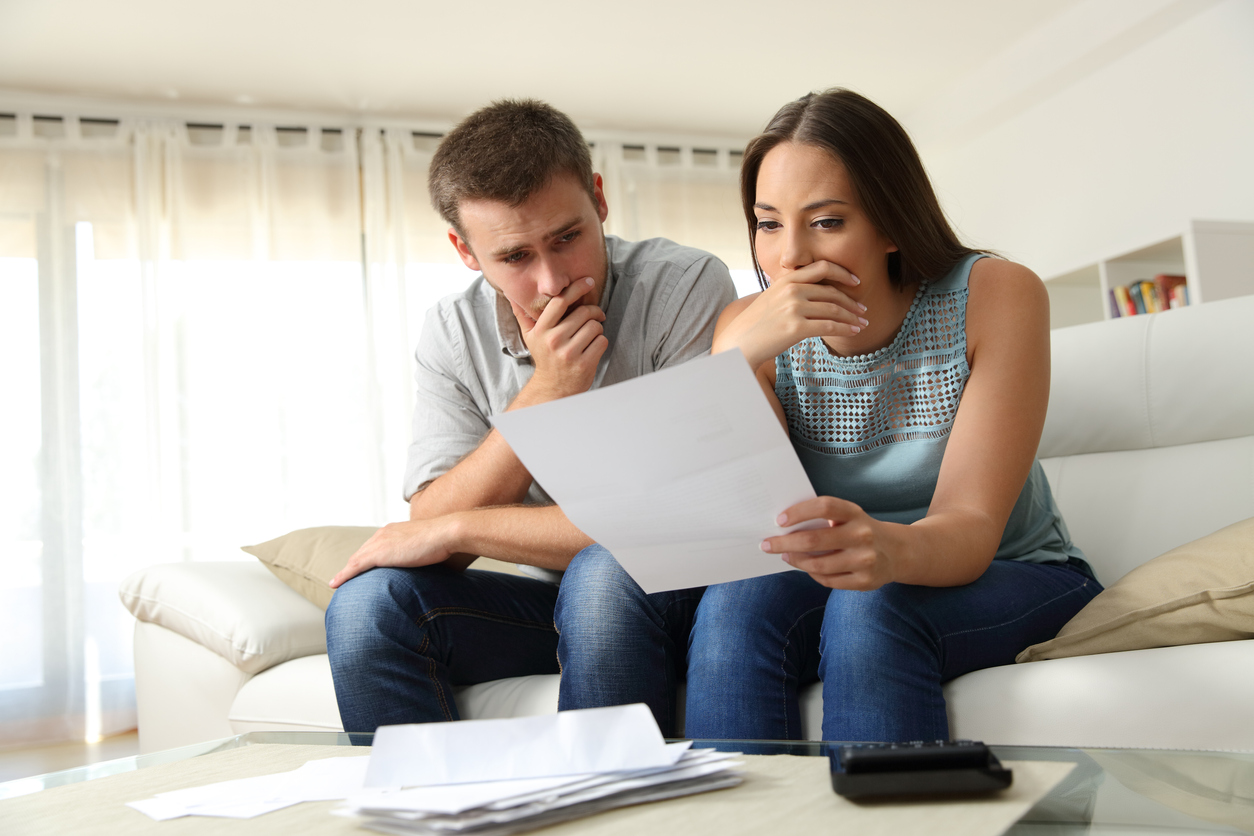 Worried couple reading a letter at home stock photo