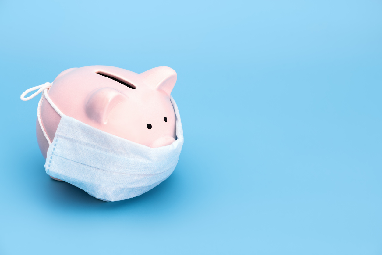 Pink piggy Bank stands on a blue medical background in a medical mask