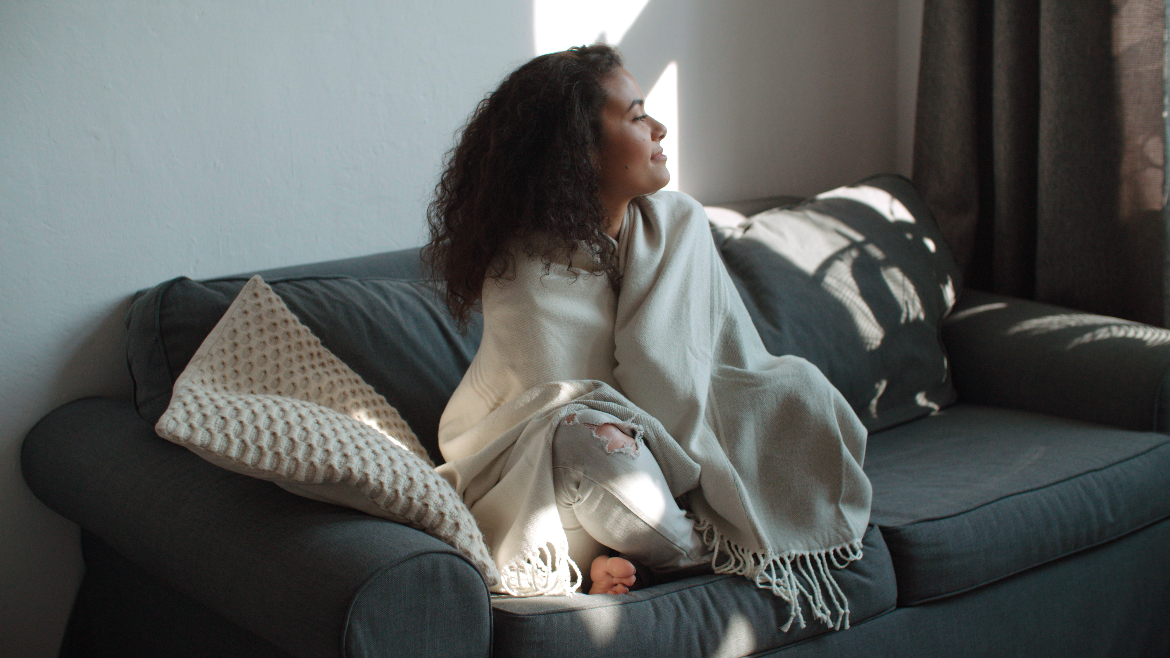 woman sitting on couch covered in a blanket