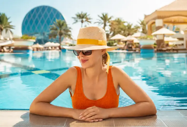 Woman relaxing at a resort pool, representing RentCafe Rewards travel perks