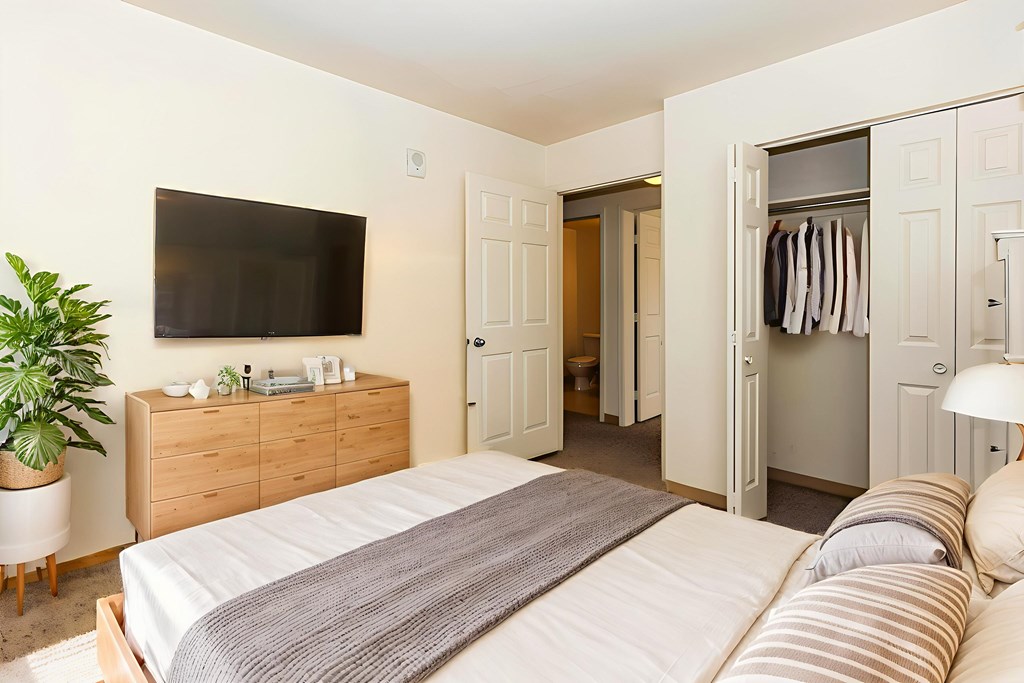 A bedroom with a bed, a TV, and a cabinet.