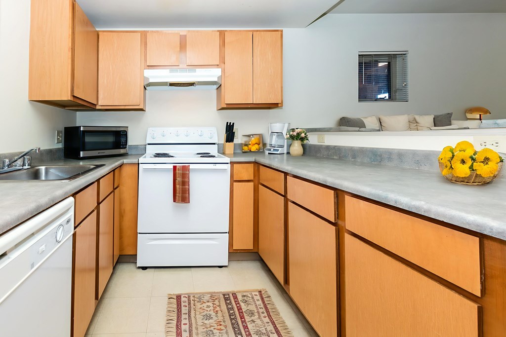 A kitchen with a white stove and wooden cabinets.