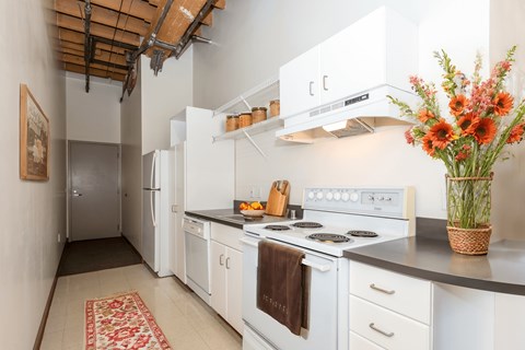 a kitchen with white appliances and a vase of flowers