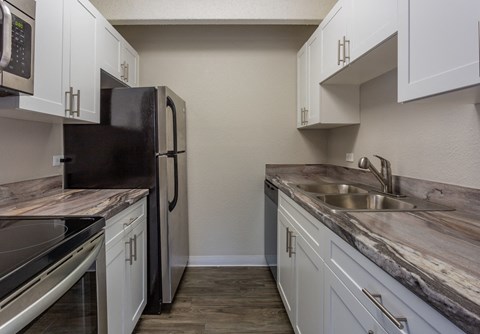 a kitchen with white cabinets and a stainless steel refrigerator