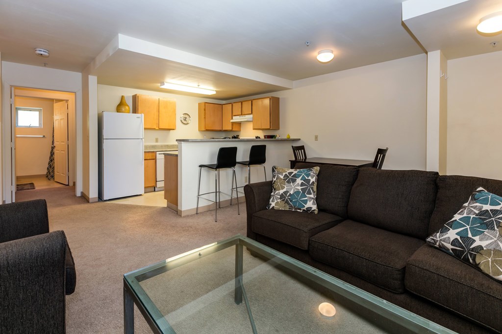 A living room with a couch, chairs, and a glass table.