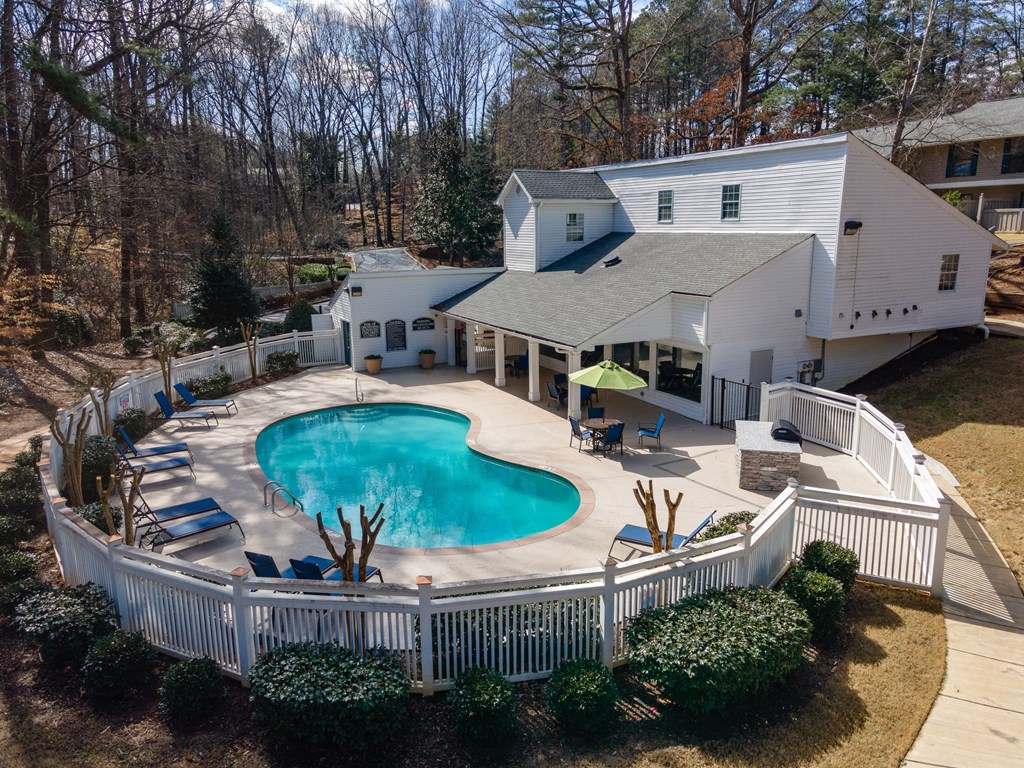 a backyard with a pool and a house with a white fence around it