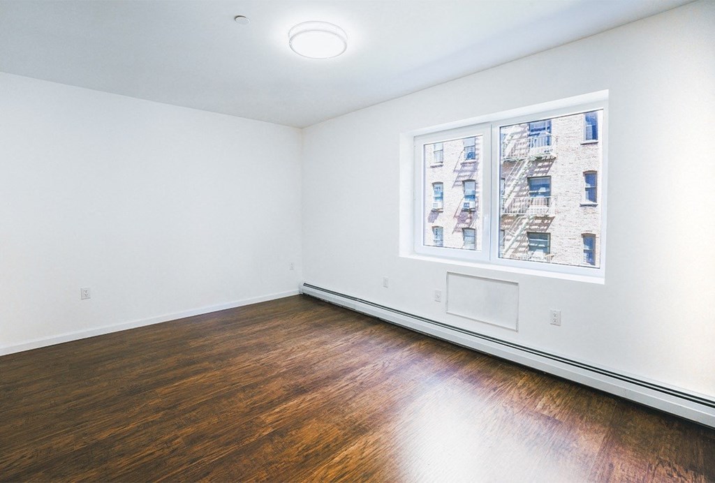 an empty room with wood floors and a window