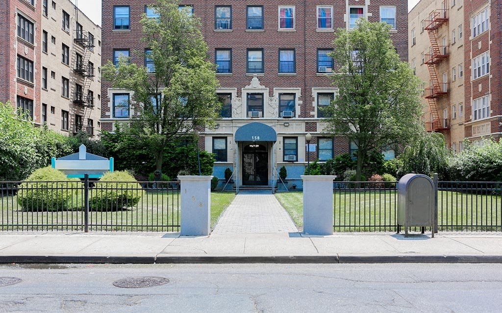 the front of an apartment building with a sidewalk and a gate