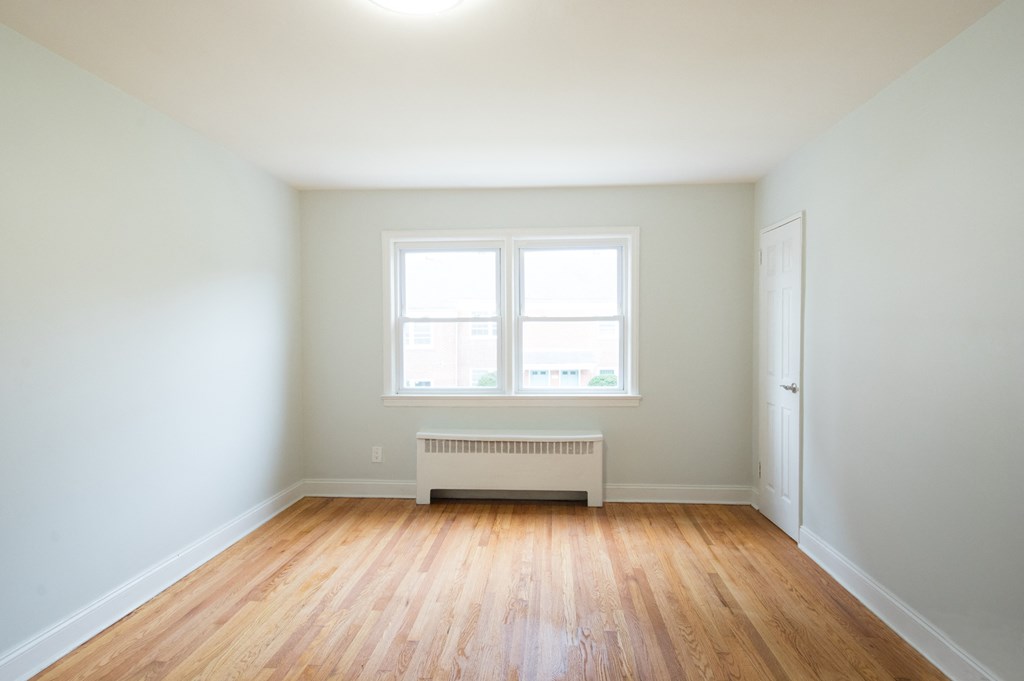 an empty room with wooden floors and a window