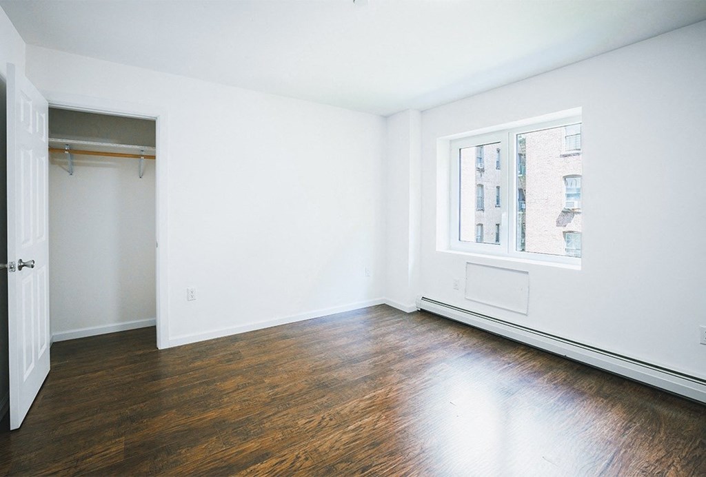 an empty room with white walls and wood floors and a window