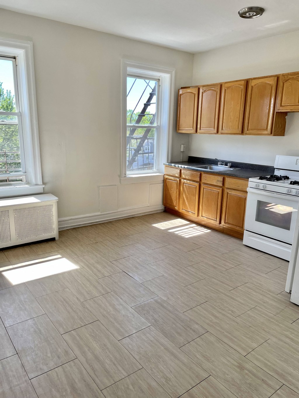 an empty kitchen with wooden cabinets and a stove and a window