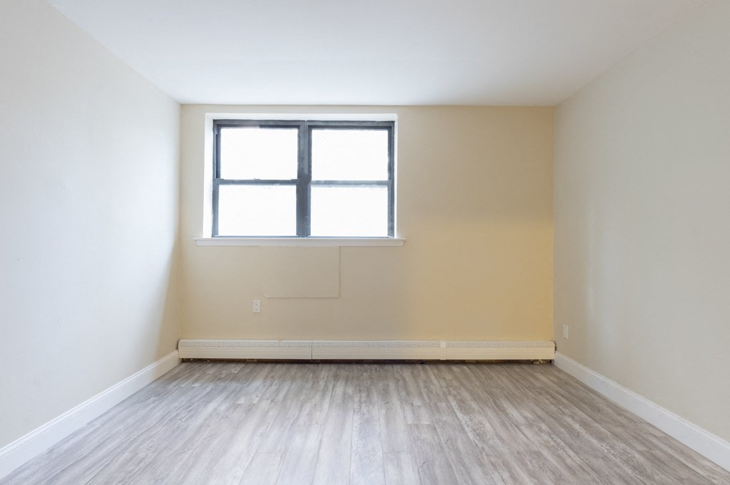 an empty room with a window and wood floors
