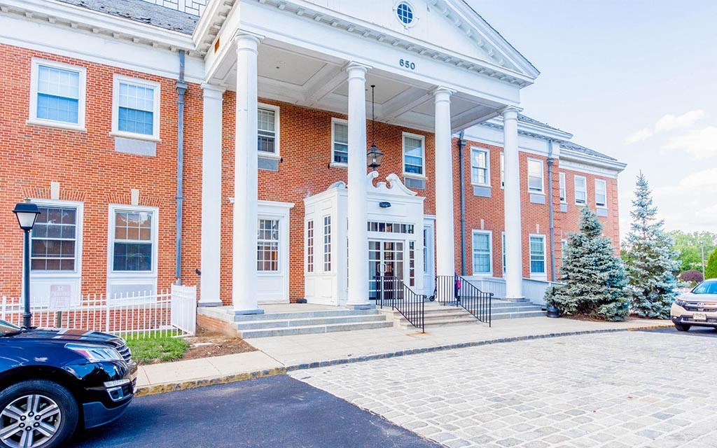 the front of a brick building with pillars and a car parked in front