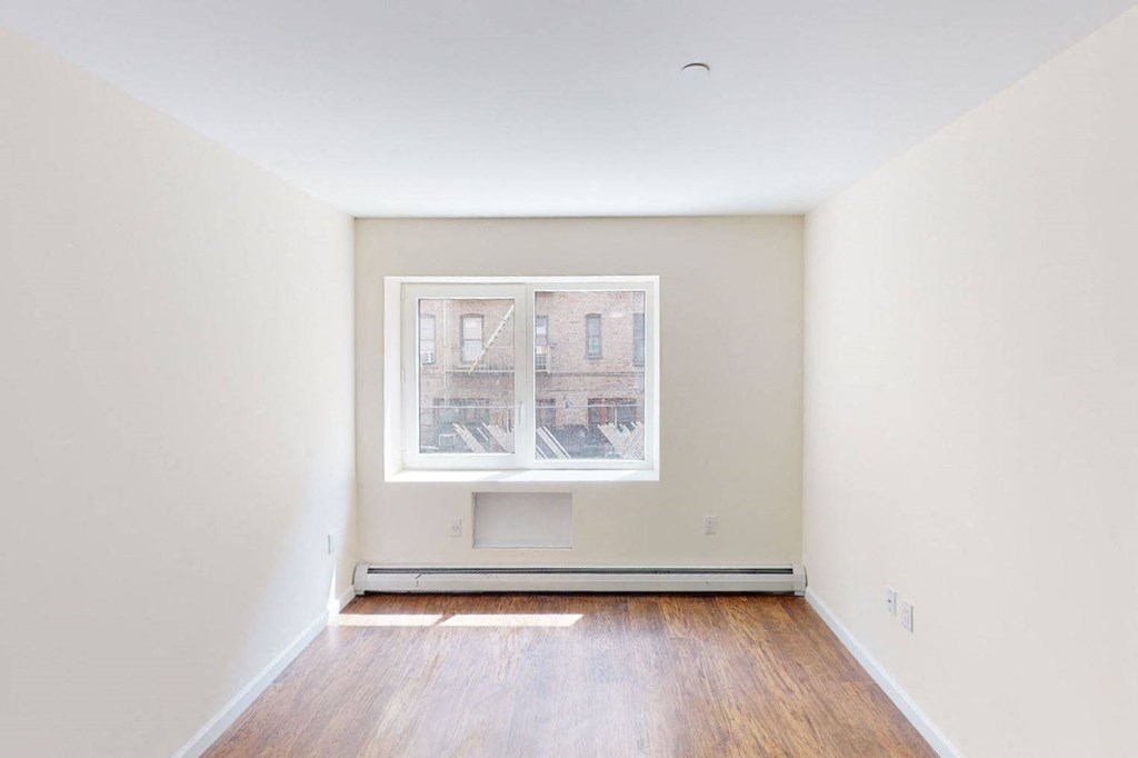 a empty room with a window and wooden floors