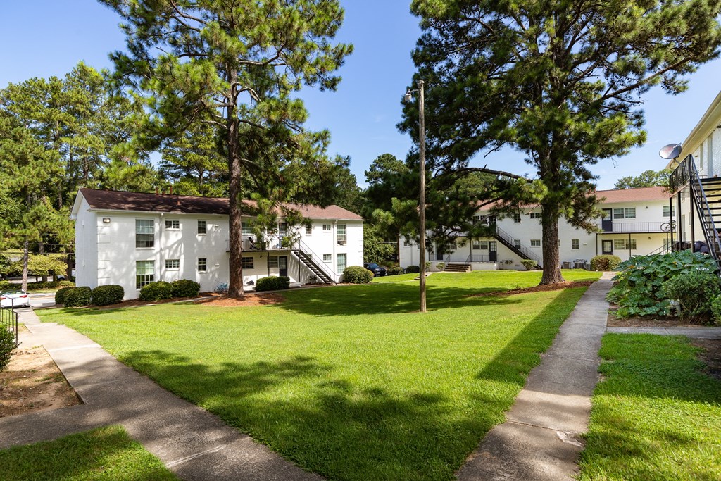 exterior view of apartments with a lawn and trees