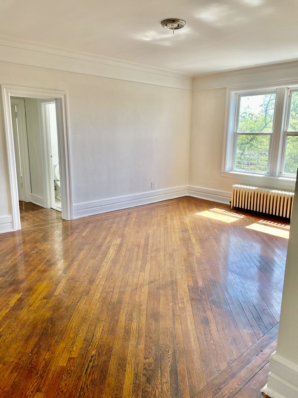 an empty living room with a hard wood floor and a window