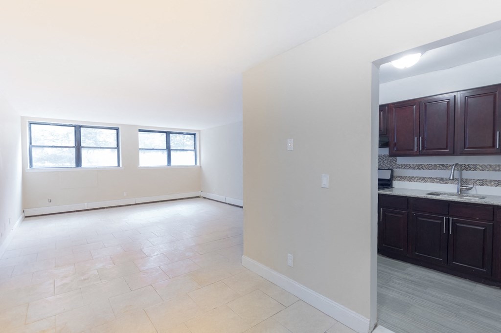 an empty living room and kitchen with dark cabinets and a large window