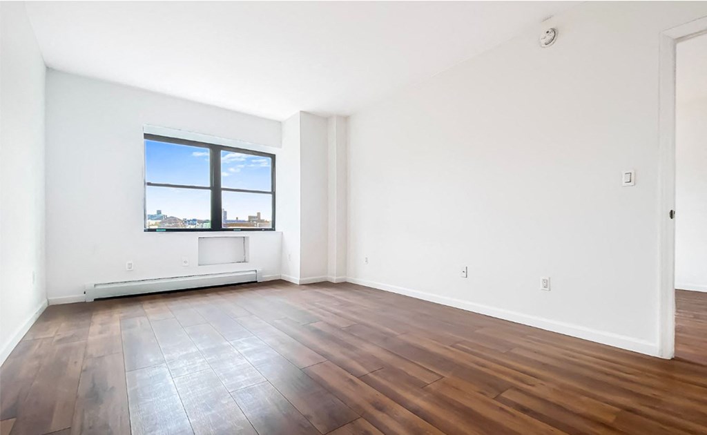 an empty living room with wood floors and a window