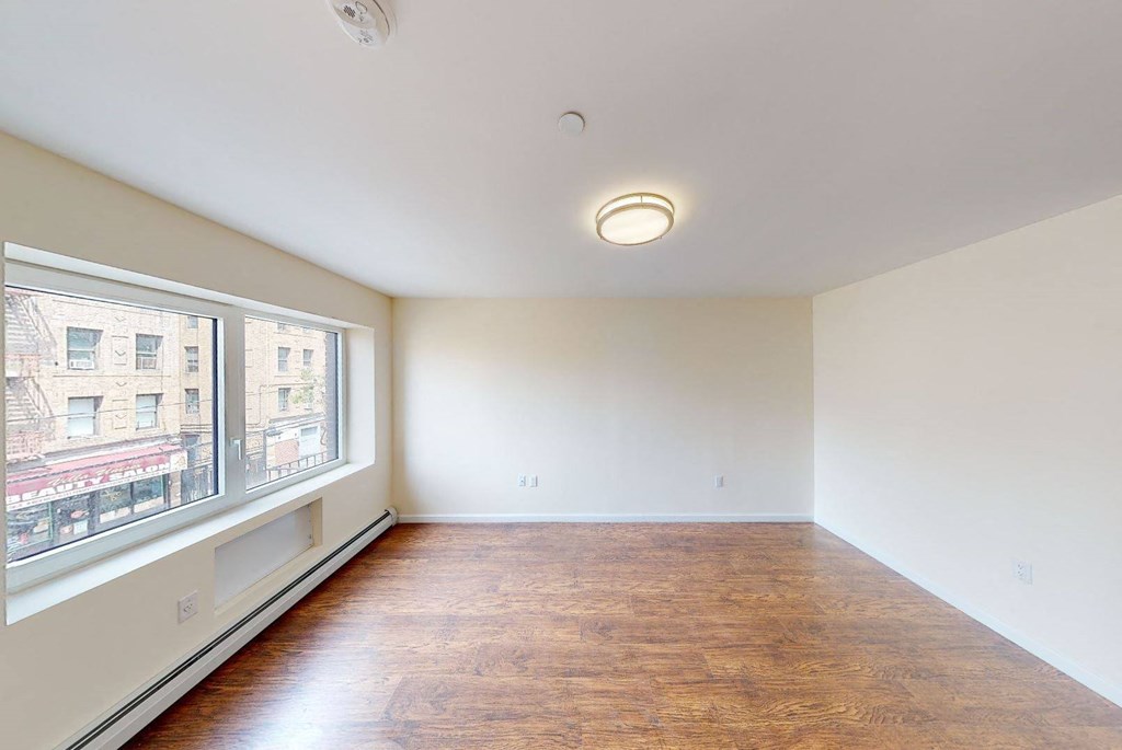 an empty living room with a large window and wood floors