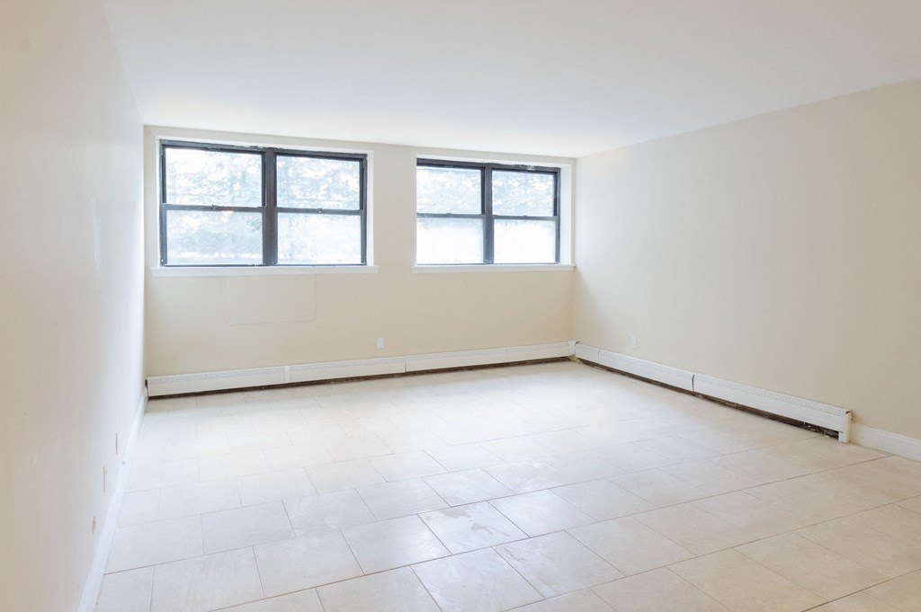 an empty room with two windows and a tiled floor