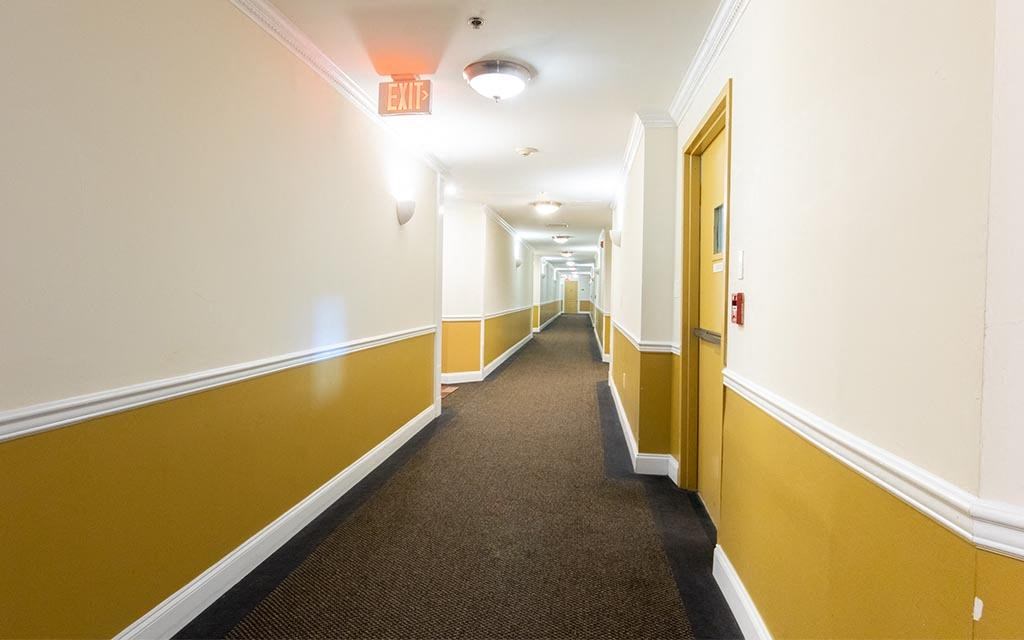 a long hallway with yellow and white walls and a brown carpet
