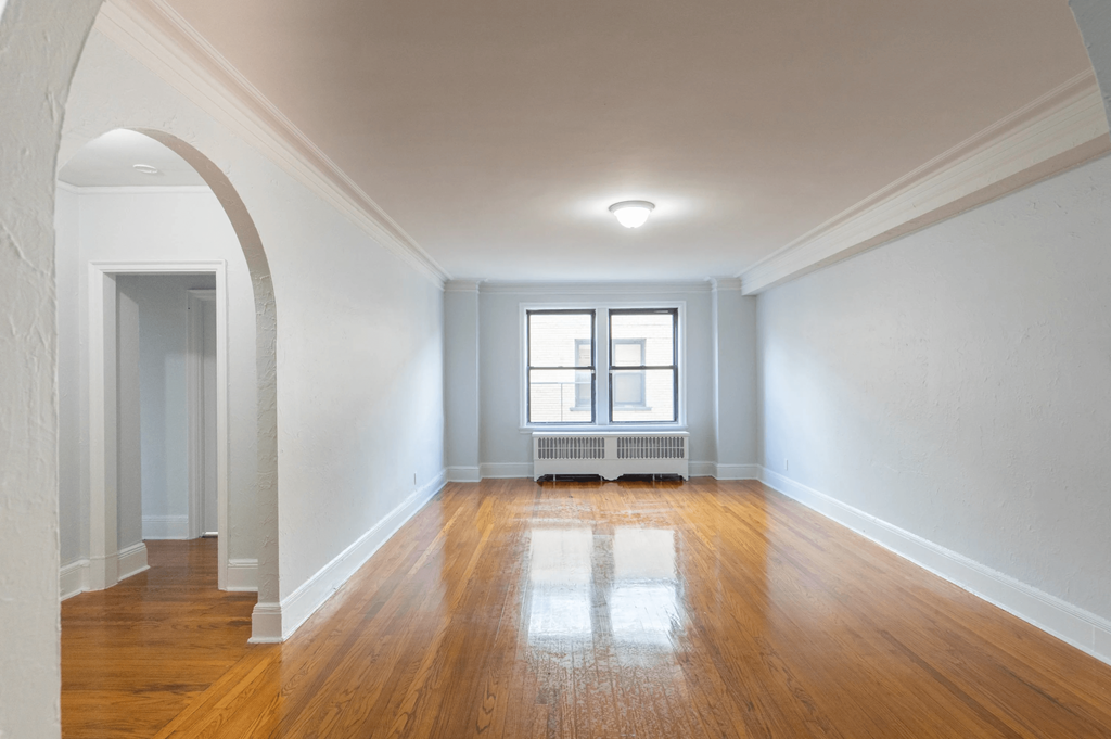 an empty living room with wood floors and a window