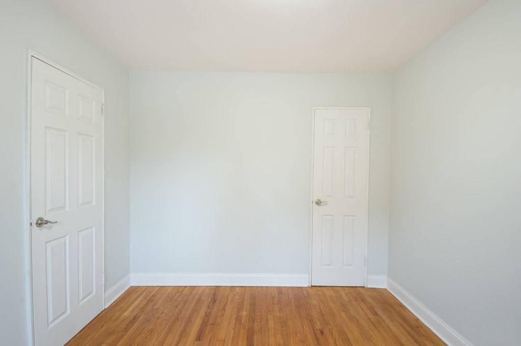 an empty room with two doors and a wood floor