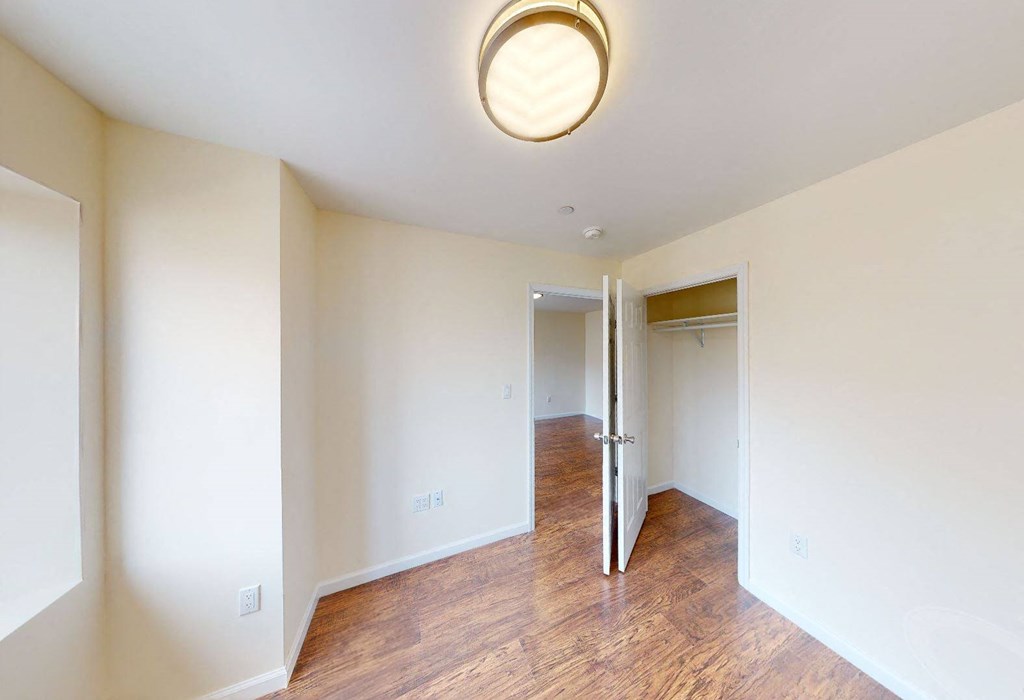 a renovated living room and hallway with wood flooring and a closet