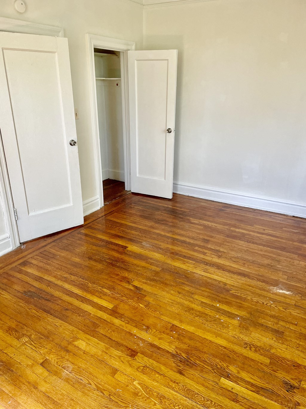 an empty room with wooden floors and white doors