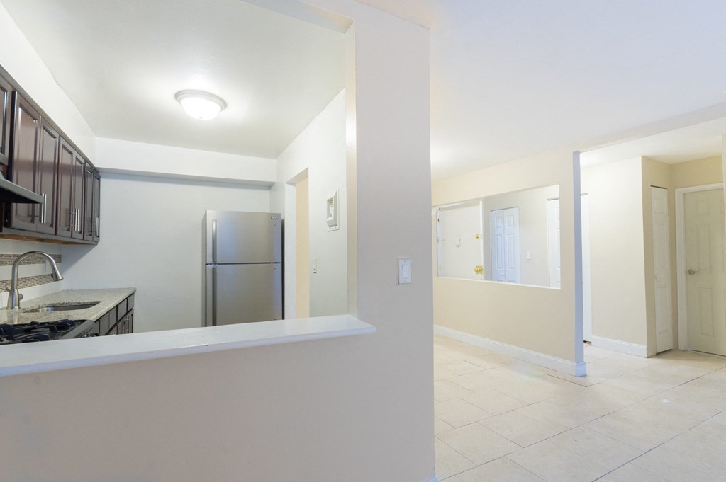 an empty kitchen and hallway with a stainless steel refrigerator