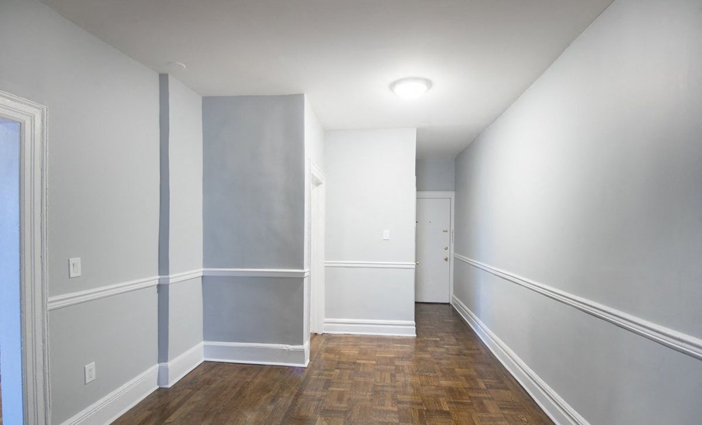 a room with grey walls and a wooden floor and a white door