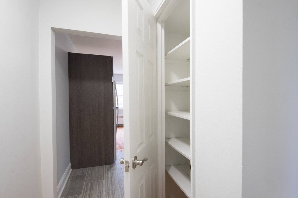 a walk in closet with a wooden door and white shelves