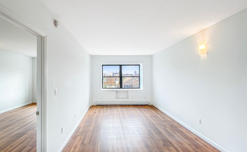 an empty room with wooden floors and a window