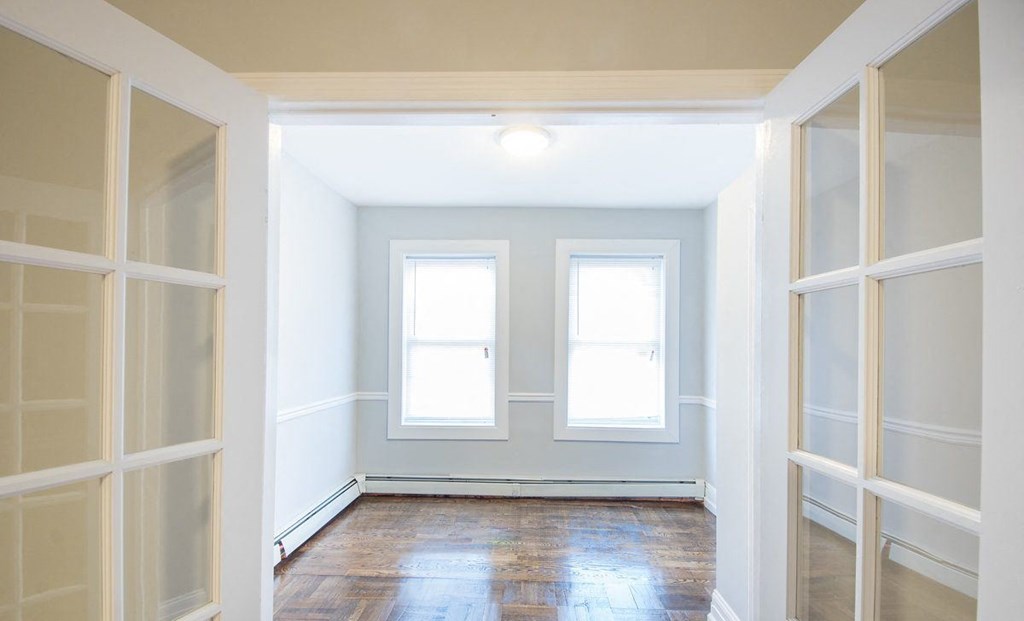 a empty room with two windows and a hard wood floor