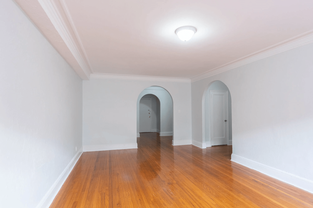 a living room with white walls and wood floors and arched doorways