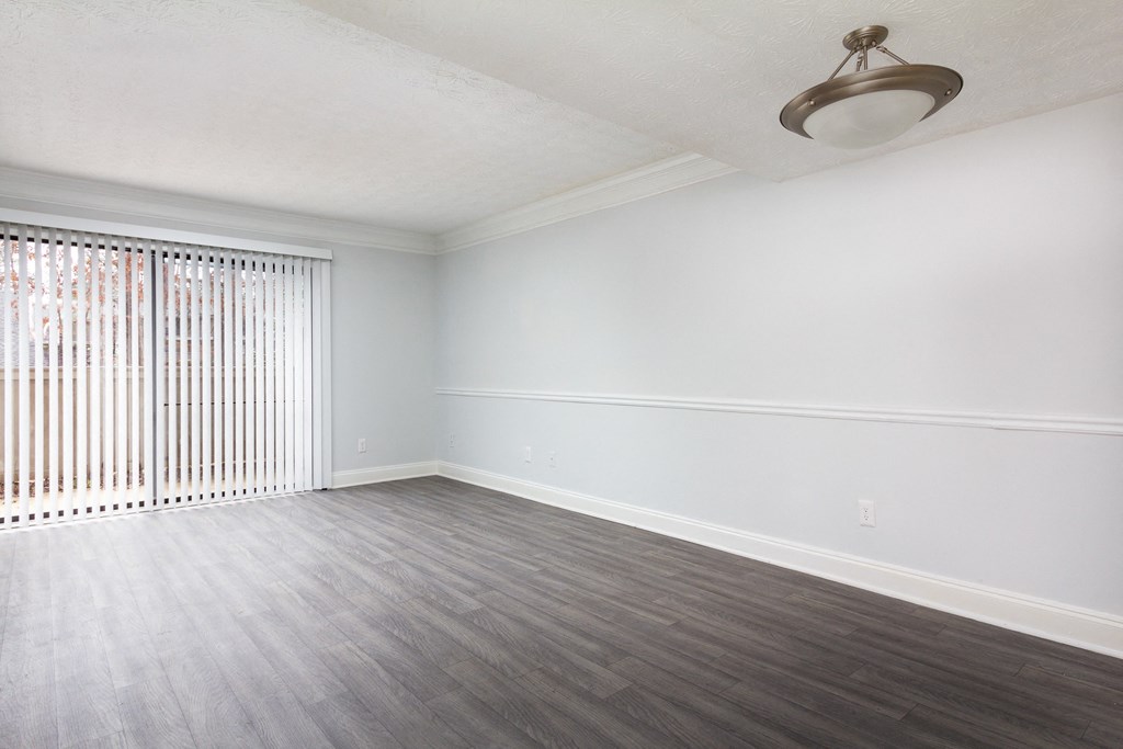 an empty living room with wood flooring and a window