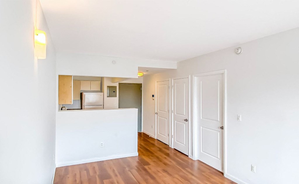 the living room and kitchen of an apartment with a wood floor