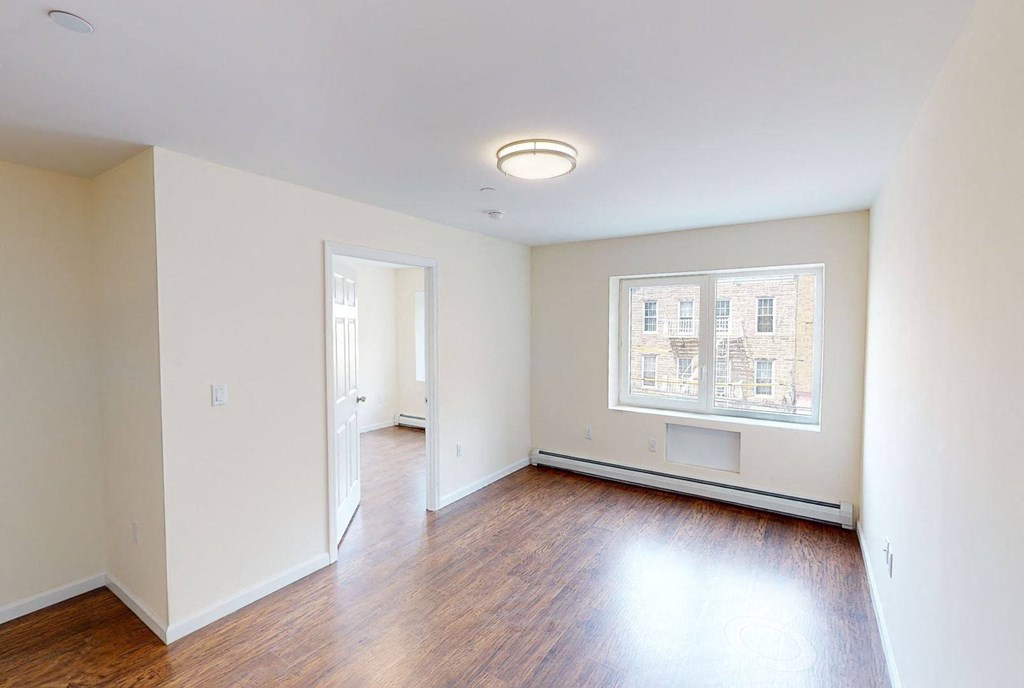 an empty living room with hard wood floors and a window