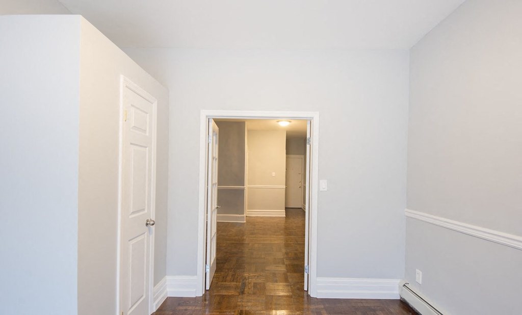 a bedroom with white walls and a door and a hallway to a closet