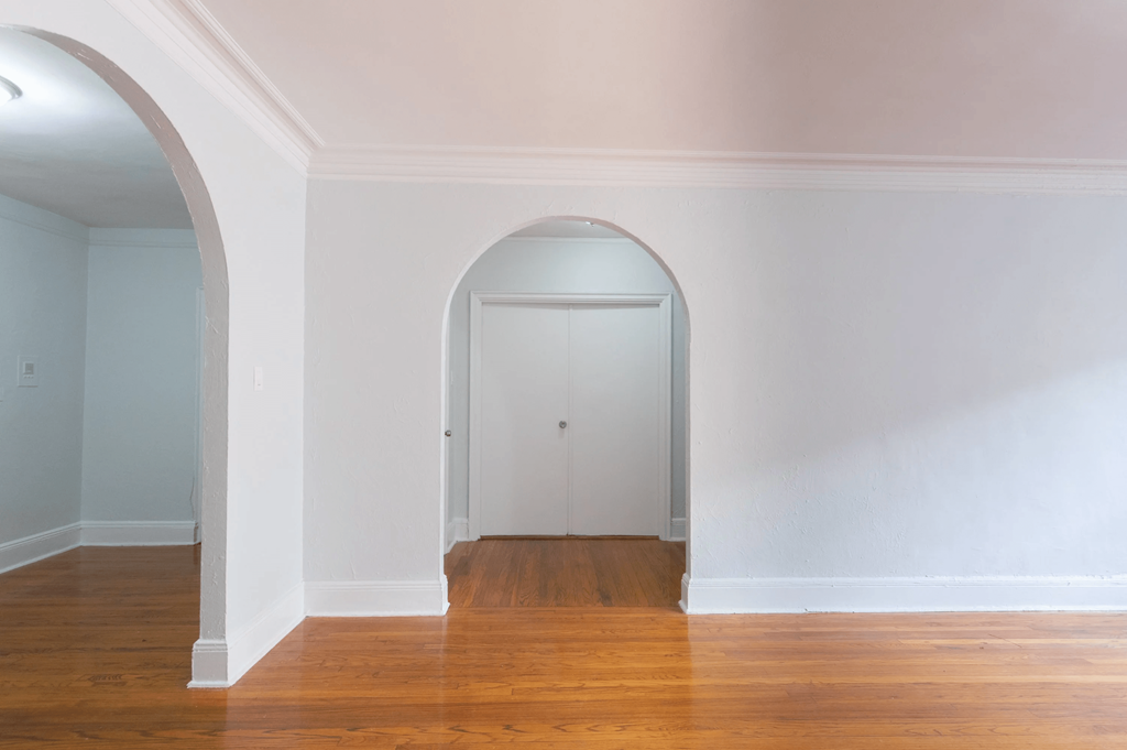 an arched doorway in a living room with wood floors and white walls