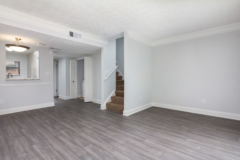 an empty living room and hallway with white walls and wood floors