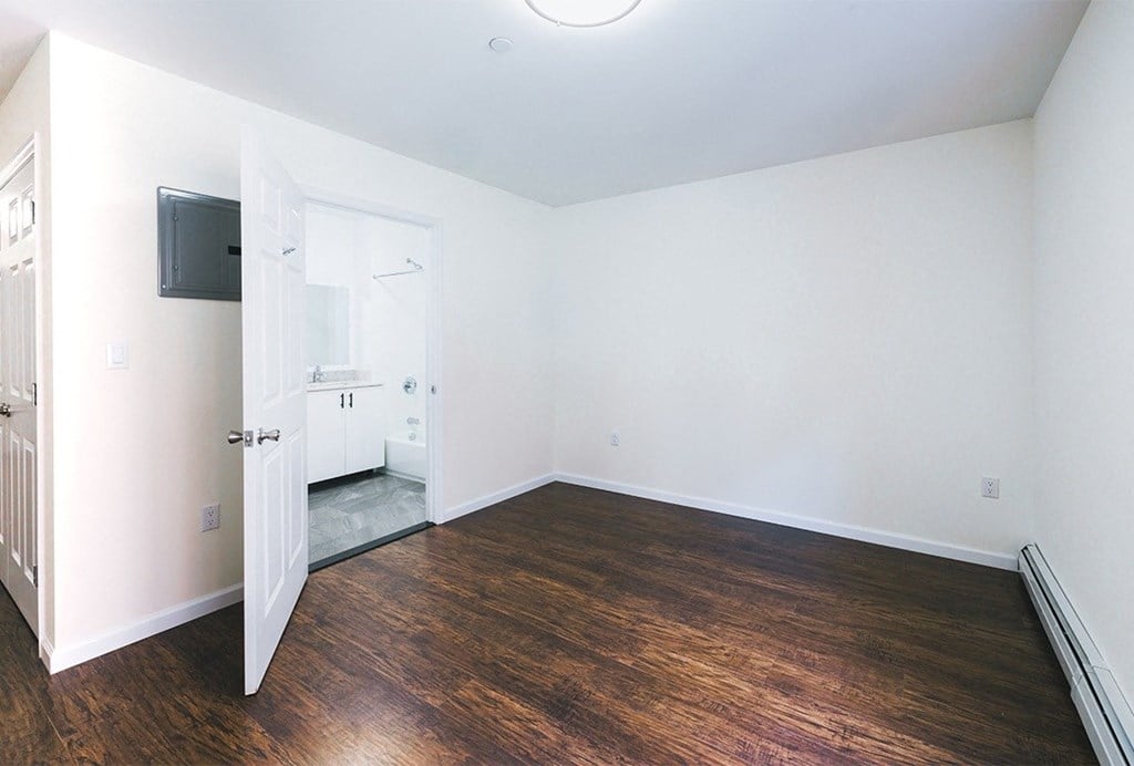 an empty living room with wood flooring and a tv