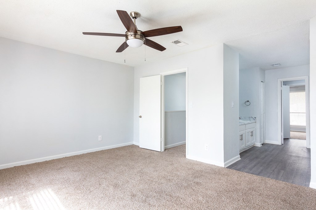 an empty living room with a ceiling fan and a bathroom