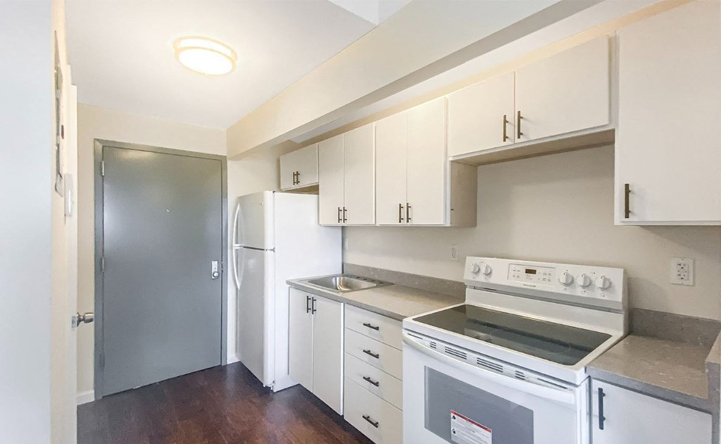 an empty kitchen with white cabinets and appliances and a refrigerator