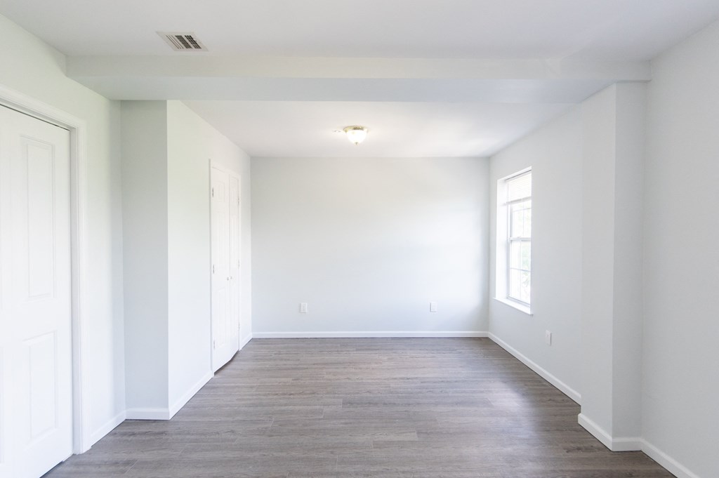 an empty room with white walls and a wood floor