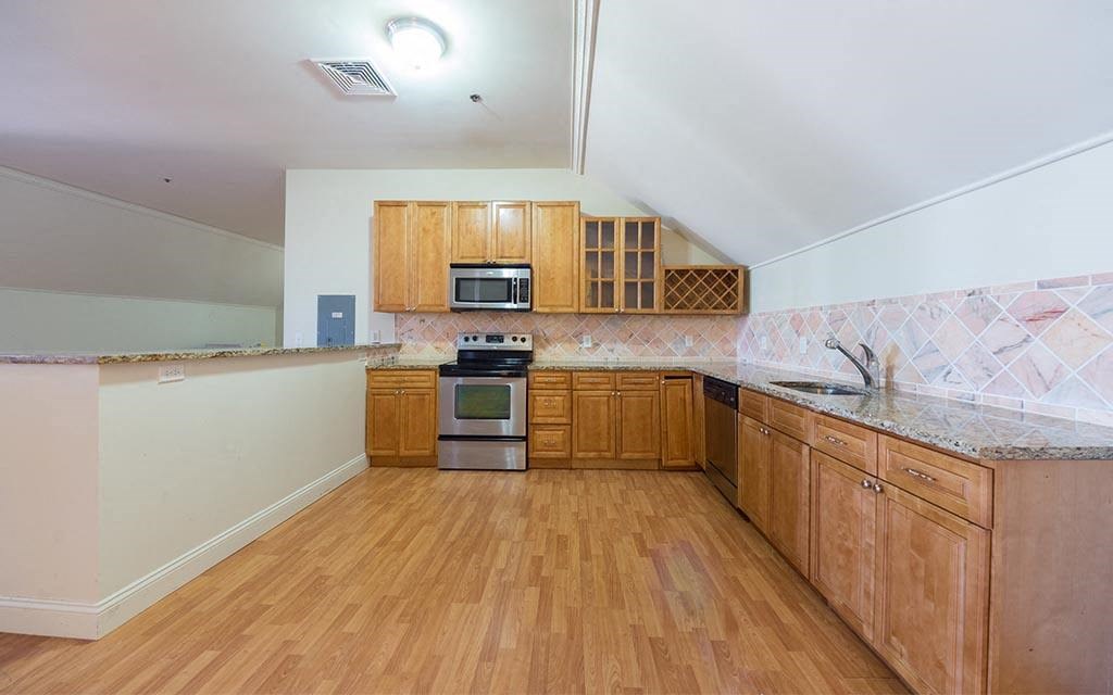 a large kitchen with wooden cabinets and a wooden floor