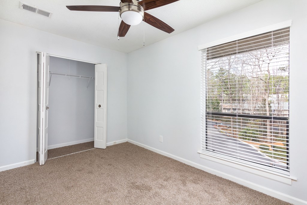 an empty room with a large window and a ceiling fan