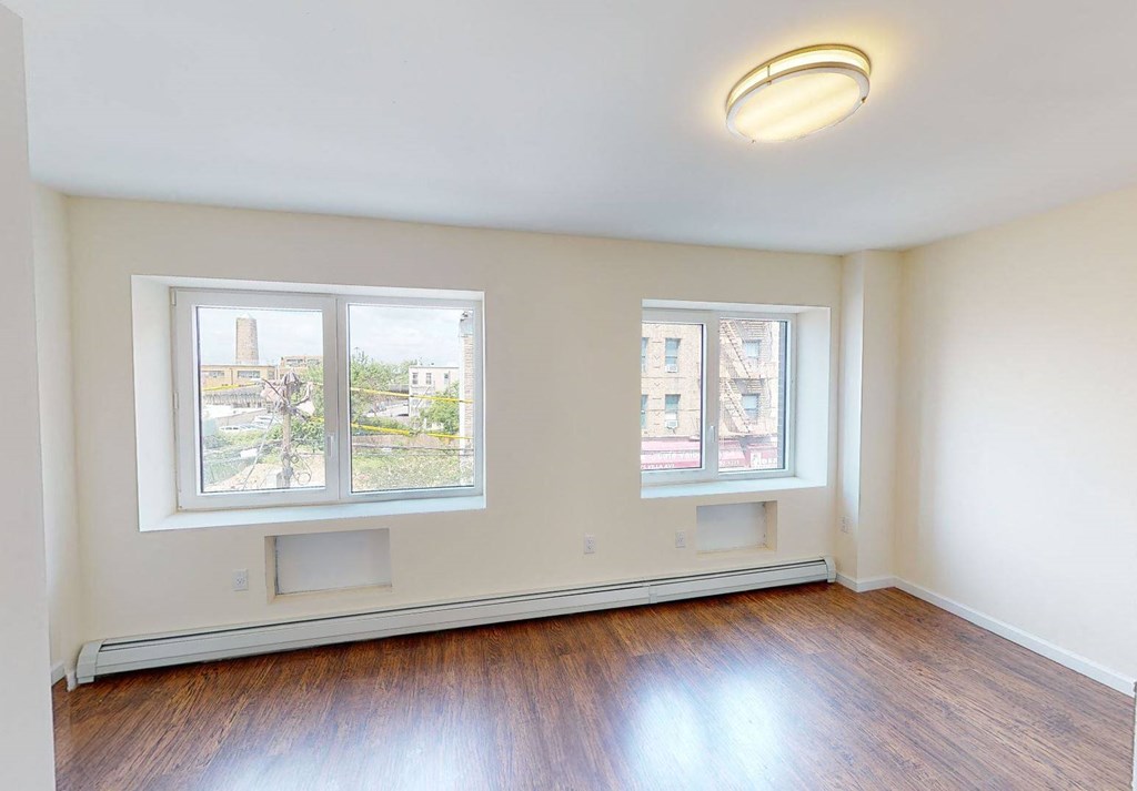 an empty living room with wood floors and two windows