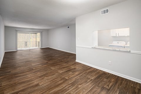 an empty living room with wood flooring and a window