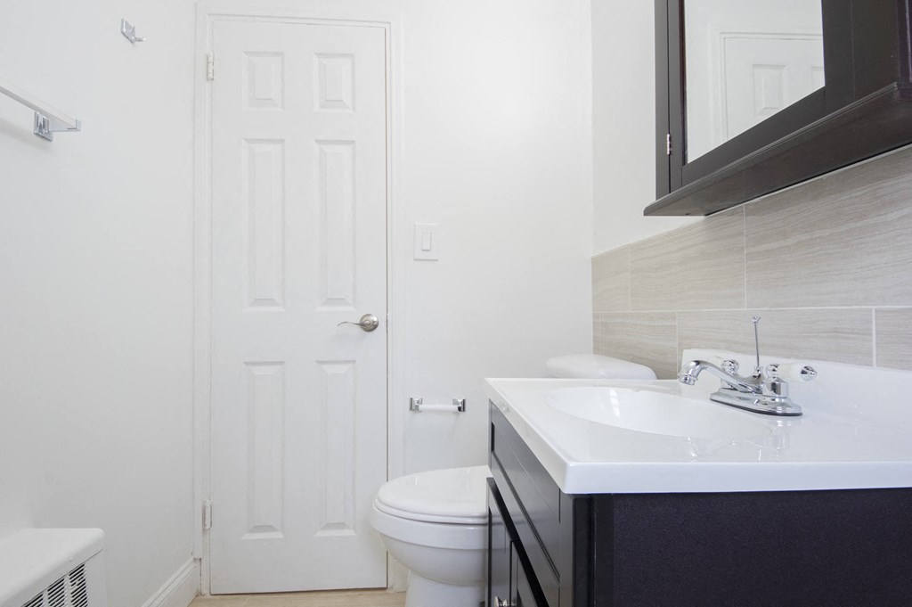 a bathroom with a toilet sink and mirror and a door